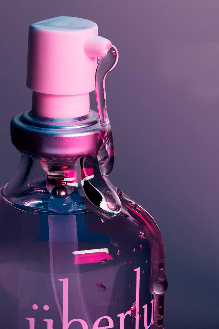 Up close view of Chicago made silicone sexual lubricant Uberlube. Glass pump bottle lit with neon lights.