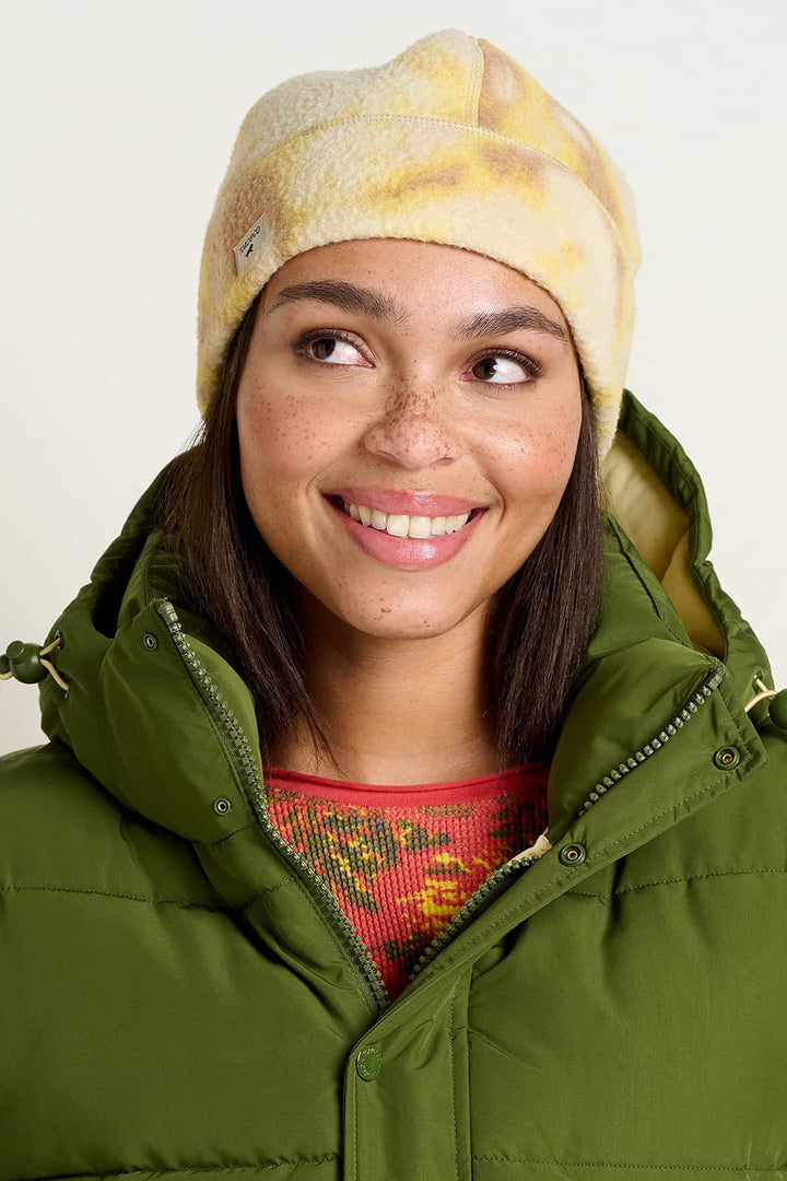 Woman wearing yellow, tan, and cream fleece tie die beanie. 