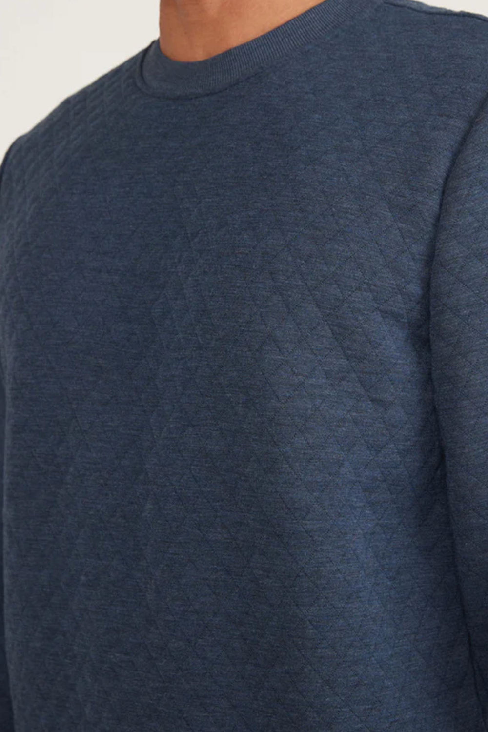 Close up view of a navy heather quilted crew sweatshirt. 