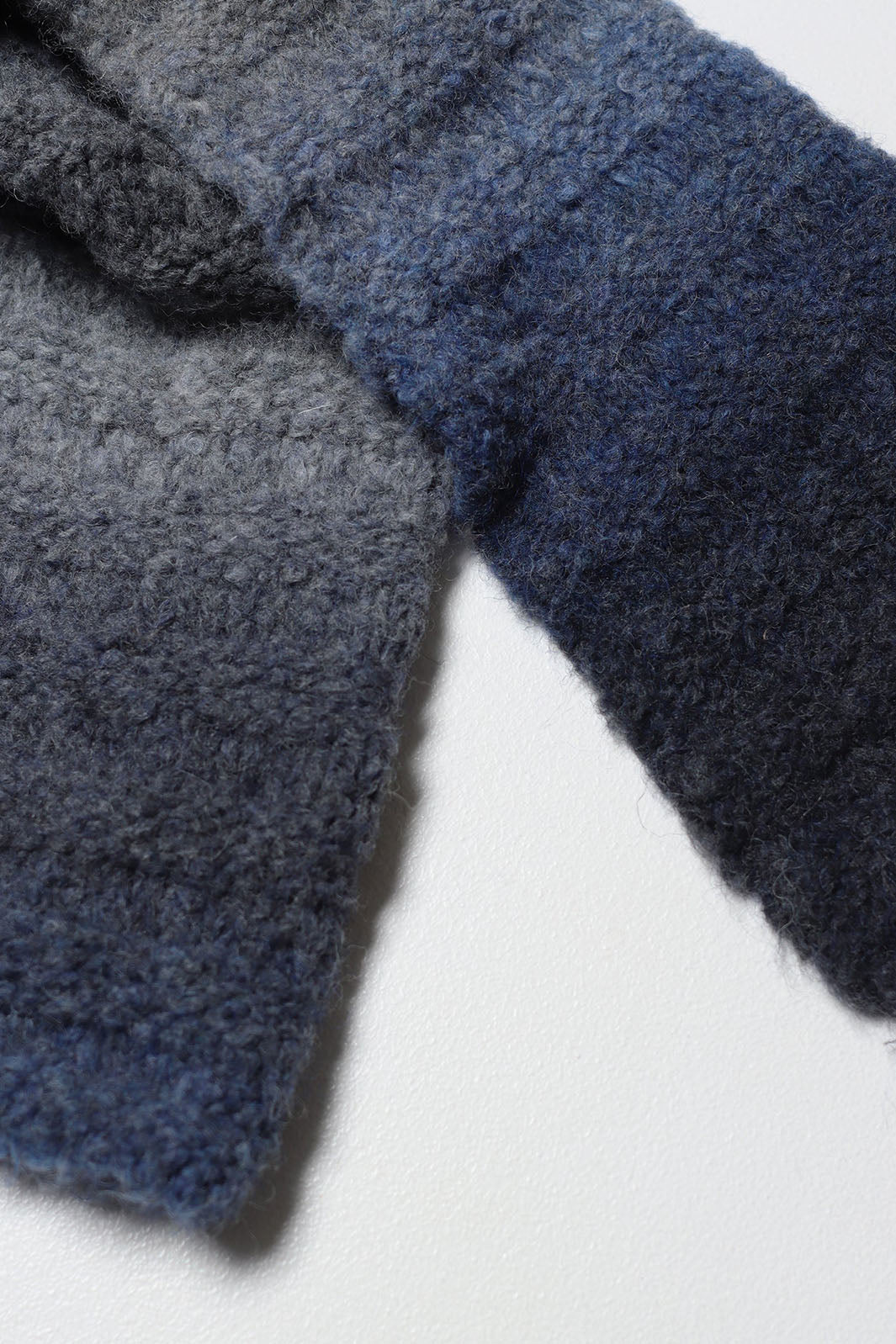 Close up of black, navy, ombre stripe knit scarf. 