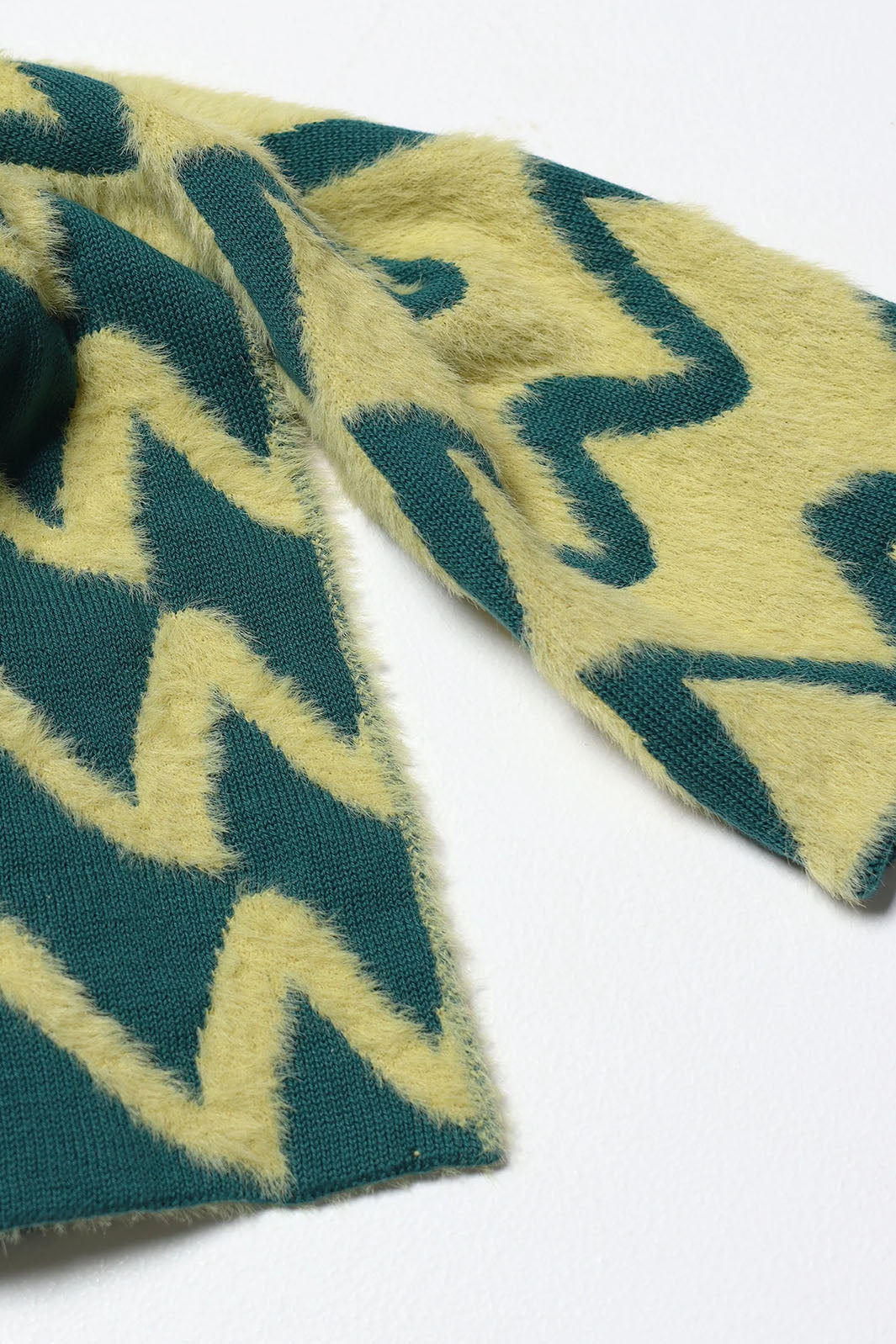 Close up view of yellow and teal fuzzy zig zag fiber scarf.