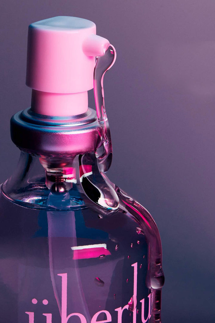 Up close view of Chicago made silicone sexual lubricant Uberlube. Glass pump bottle lit with neon lights. 